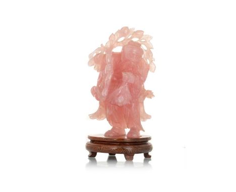 CHINESE ROSE PINK JADE QUARTZ FIGURE, EARLY 20TH CENTURY  modelled as a traveller, standing holding a bouquet of flowers and 