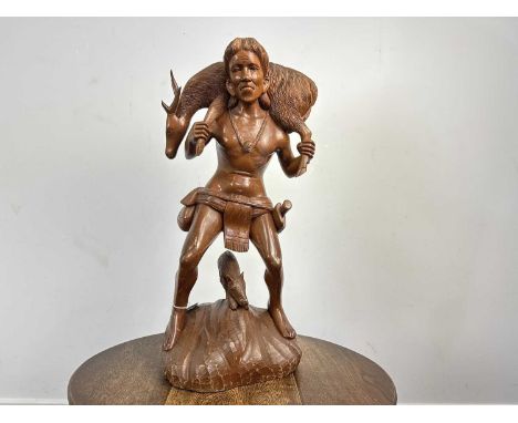 CARVED WOODEN FIGURE, 20TH CENTURY modelled as a male hunting figure, posed carrying a deer, stood above a boar on a naturali