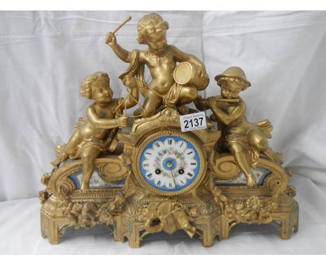 An ornate French gilt bronzed case mantel clock inset with painted porcelain panels surmounted with cherubs playing instrumen