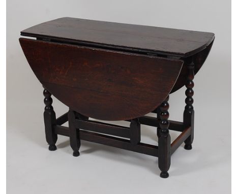 A circa 1700 joined oak gateleg table, having oval fall leaves and on bobbin turned and square cut end supports (with repairs