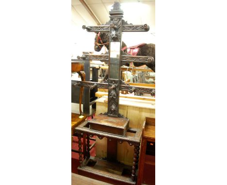 A circa 1900 heavily carved oak hall stand, having a mirror inset, 10-turned hooks and hinged compartment, raised on bobbin t