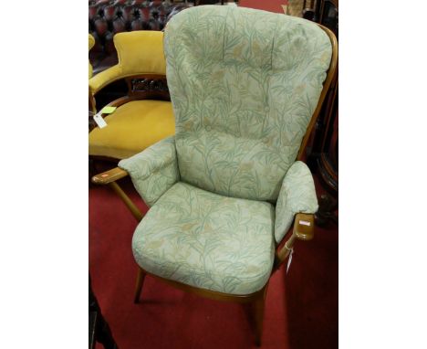 A contemporary Ercol mid elm stickback armchair, having green floral upholstered cushion back and seat