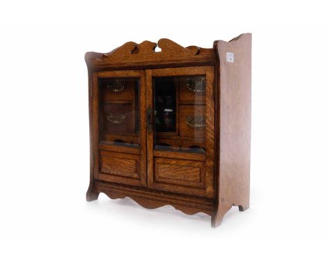 LATE VICTORIAN SMOKER'S OAK CABINET with a pair of glazed doors opening to reveal small drawers and a ceramic tobacco jar, 41