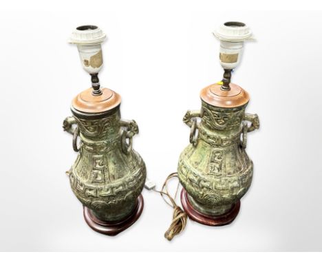 A pair of 20th century patinated metal lamp bases in the Chinese archaic style with ring handles on hardwood bases, overall h