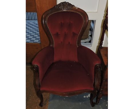 A Victorian style mahogany spoon-back button upholstered armchair, on cabriole legs and covered in a red fabric..