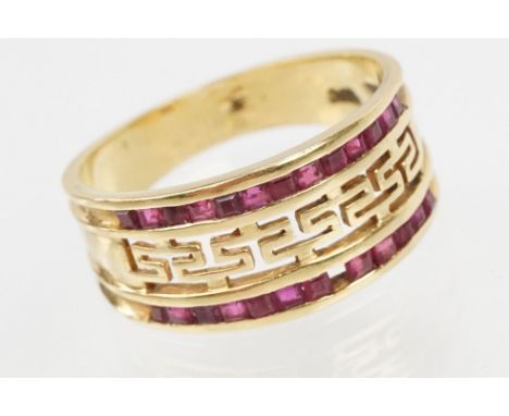 18ct gold and ruby ring having a pierced Greek key design head with two rows on channel set step cut rubies. Marked 750. Size