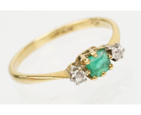 18ct gold diamond and emerald three stone ring. The ring being set with a square step cut emerald flanked by two round cut di