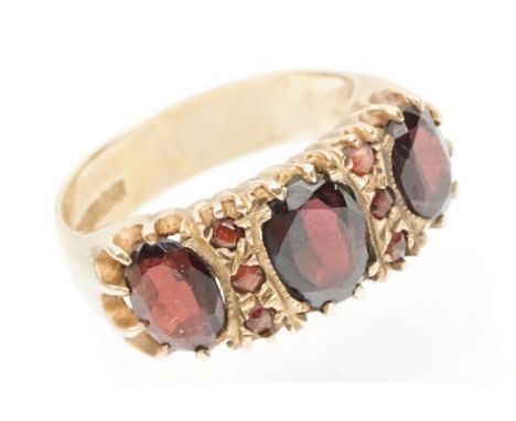 9ct gold and garnet ring being set with three oval cut garnets with round cut accent stones. Hallmarked Birmingham 1972. Size