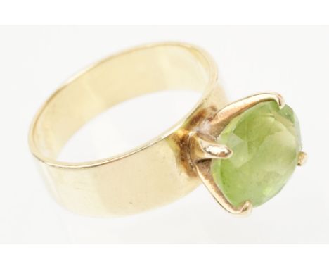18ct gold and peridot dress ring. The ring being set with an oval cut peridot in a four prong setting to a plain wide band. M