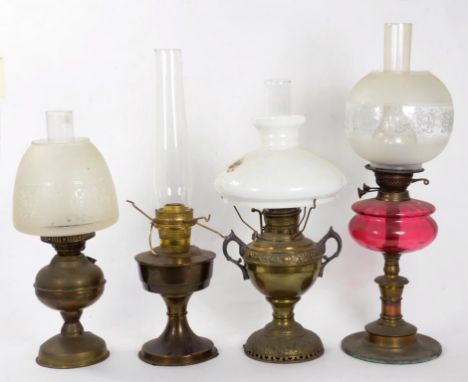 A BRASS OIL LAMP WITH CRANBERRY GLASS FOUNT AND GLASS SHADE 55CM H AND THREE OTHER BRASS OIL LAMPS