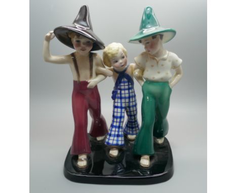 A 1930s Goldscheider figure group of two young boys, wearing pointed hats, striding arm in arm with a small girl in chequered