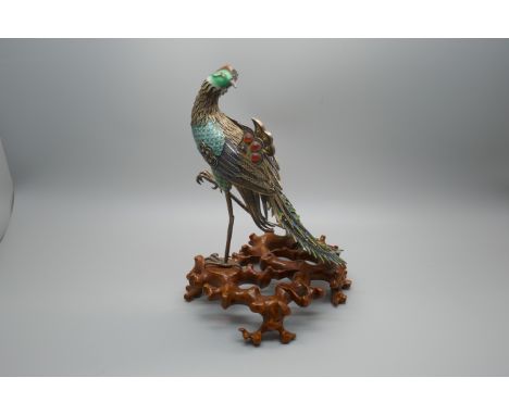 A Chinese silver gilt and enamelled model of a peacock, one amber enamelled piece missing, affixed to a wooden stand, 18cm 