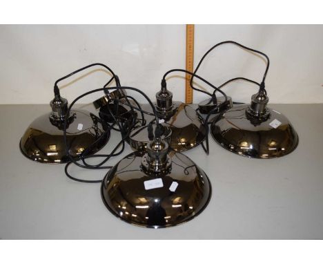 A group of four modern hanging metal pendant light fittings in the industrial style