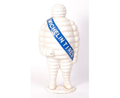A cast iron Michelin Tyres ' Bibendum ' mascot advertising figure / doorstop. White, with blue sash. Mounted on a half-moon b