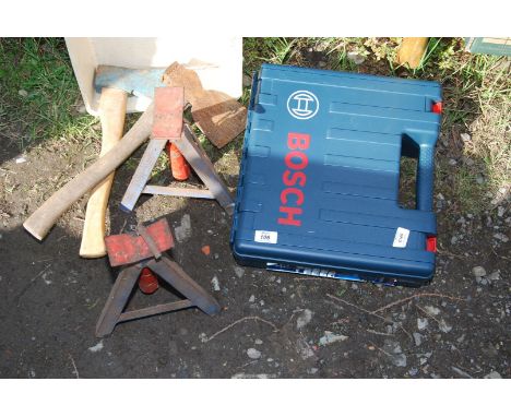 A pair of axle stands, two axes and an empty drill box.