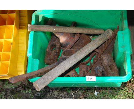 A box of metal implements, pick axe head, rake, sledgehammer heads, etc.