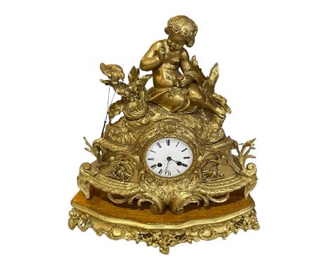 Large ornate gilt metal mantel clock with mounted cherub on giltwood base.