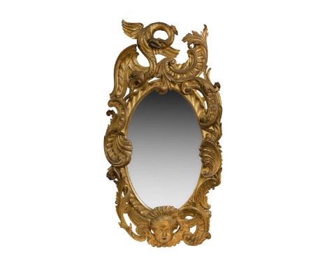 A Rococo style carved giltwood wall mirror, 19th century, with oval plate, the frame decorated with a winged beast, C-scrolls