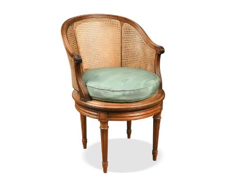 A Louis XVI style caned swivel action bergere chair, circa 1900, the moulded top rail terminating in scrolled arms, the seat 