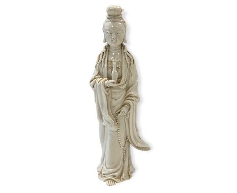 A Chinese Dehua standing figure of Guanyin, Goddess of Mercy, 18th/19th century, with smiling expression, wearing robes and j