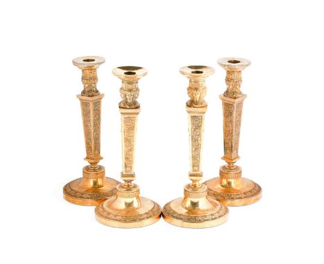A set of four gilt metal classical style candlesticks, 19th century, each with four female masks above tapering square column