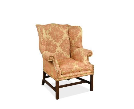A George III mahogany framed wing back armchair, the shaped arched back with outscrolled arms, upholstered in a red and cream