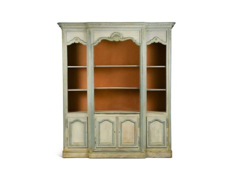 A French provincial style painted breakfront bookcase, with moulded arched tops above open shelves and four cupboard doors on