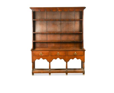 A George III oak farmhouse dresser, the boarded plate rack with moulded cornice over three shelves, the base with three drawe