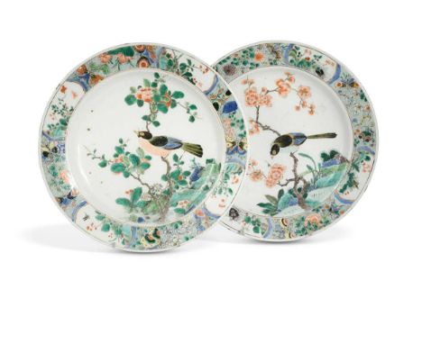 A pair of Chinese famille verte plates, Kangxi (1662-1722), painted with magpies perched on prunus blossom within repeating b