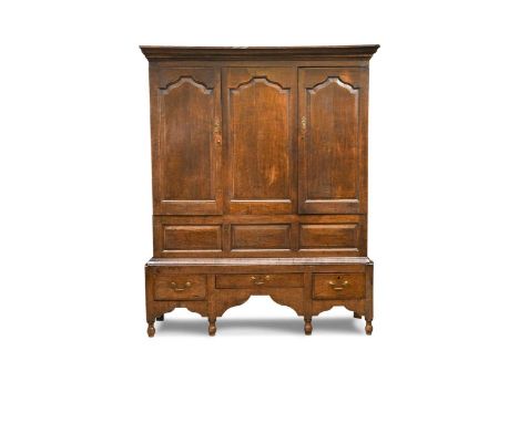 An oak livery cupboard, 18th century, the moulded cornice above a pair of arched fielded panelled doors and conforming centra