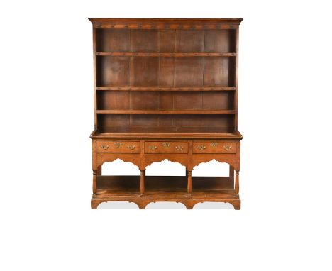 A George III oak kitchen dresser, the moulded cornice above a boarded plate rack with three shelves, the base with three frie