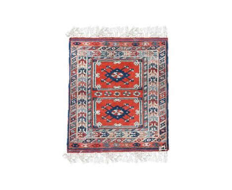 A hand-knotted Turkish tribal rug, late 20th century to a Kazak design with two indigo medallions on a madder ground, and wit