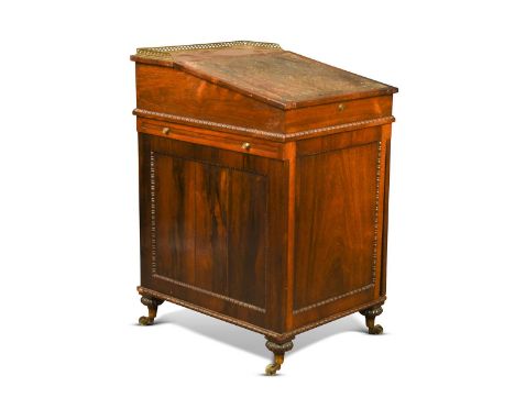 A rosewood slide top Davenport, early 19th century, after a design by Gillows, the sliding upper section with three quarter p