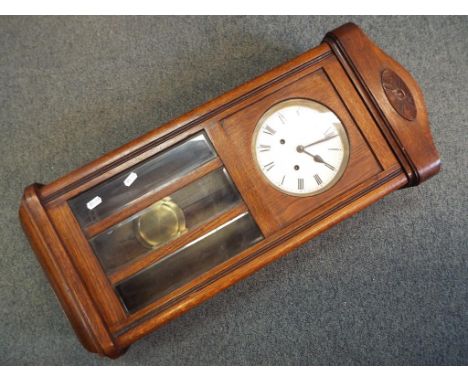 An oak cased wall clock, Roman numerals to the dial, with key and pendulum.