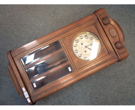 An oak cased wall clock, Arabic numerals to the dial, with key and pendulum.
