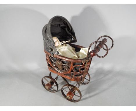 A vintage miniature pram, ca 1950s with ceramic headed doll of the period, marked to the back of the neck 8535