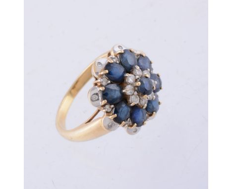 A sapphire and diamond ring, the central circular cut sapphire within a cluster surround of brilliant cut diamonds, and oval 
