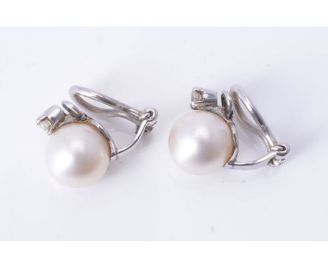 A pair of ear clips, modern, each with an 8.5-9mm diameter light cream cultured pearl and a claw set round brilliant-cut diam