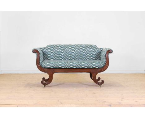 A Regency mahogany settee, c.1820, with a reeded frame and scrolling supports terminating in brass castors, upholstered in vi