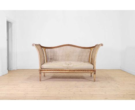 A Louis XVI-style painted wooden settee, c.1900, with a scrolling frame and caned panel sides and back, above a tapestry cove