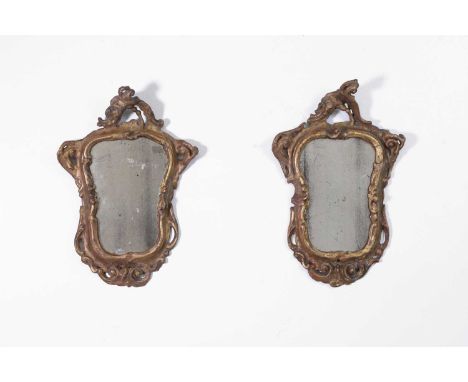 A pair of small rococo giltwood mirrors, mid-18th century, Italian, each with a scrolling foliate frame enclosing a mercury g