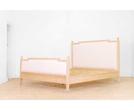 A carved wooden double bed in the French taste, of recent manufacture, with an upholstered headboard and footboard,188cm wide