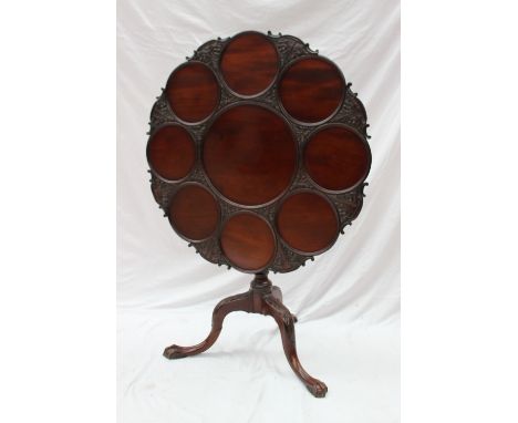 A George III mahogany tripod table, the circular top with separate plate wells on a turned and carved base, 82cm diameter