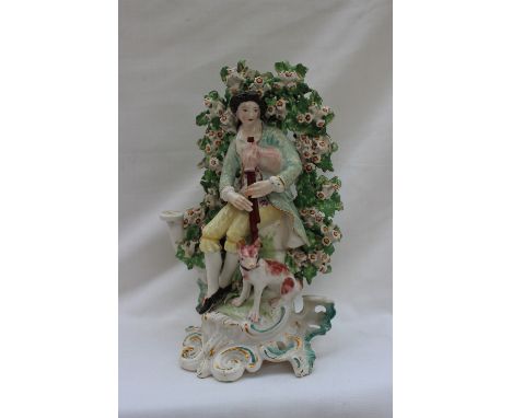 An 18th century English pottery bower group of a man playing bagpipes with a dog at his feet on a rococo scrolling base, prob