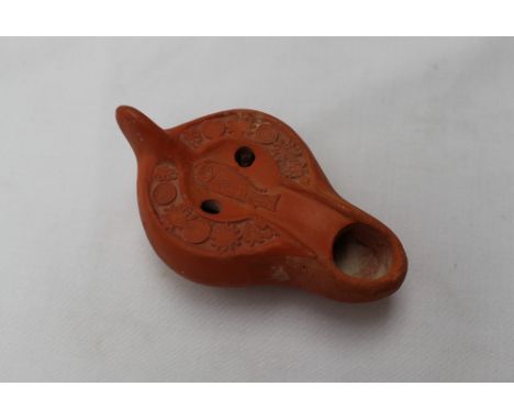 A Roman terracotta oil lamp, moulded with fish and flower heads, 11cm wide