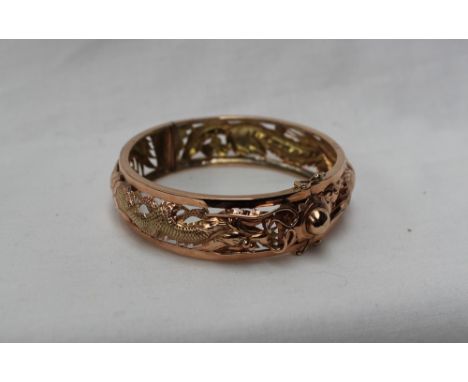 A Chinese yellow metal hinged bangle, pierced decoration of a dragon and bird of paradise, approximately 25 grams   CONDITION