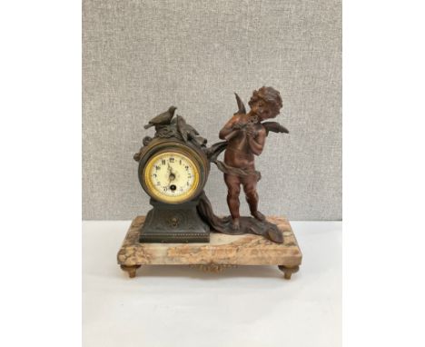 An Art Deco spelter and marble mantel clock, winged putto “Flute Enchanter” beside waisted clock, raised on gilt, 33.5cm tall