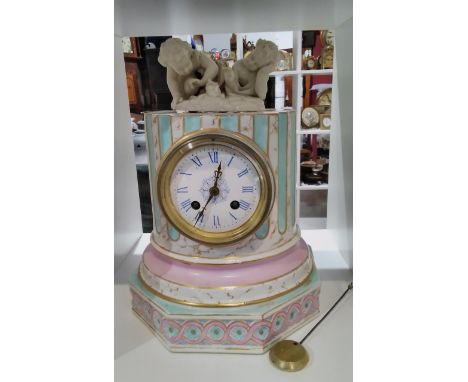 A 19th Century French ceramic column form clock with associated figural group to top, enriched with gilt, 31cm tall, with pen