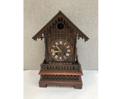 An early-mid 20th Century cuckoo mantel clock with pierced and fretwork detail, Roman dial, 52cm tall, with pendulum 