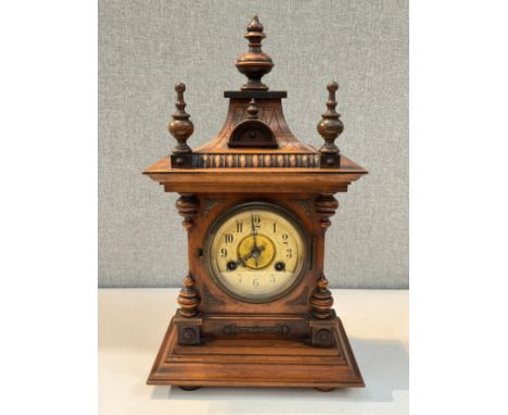 An early 20th Century walnut bracket clock, Arabic dial, architectural form case with finial detail, with pendulum 